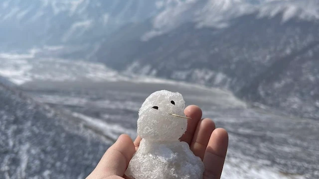 手のひらに乗せた小さな雪だるまとランタン渓谷の眺め
