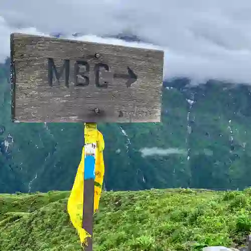 Wooden sign pointing to Mardi Base Camp (MBC), with a yellow scarf