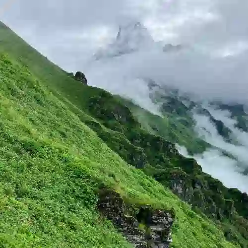 Green slope and a peak lost in cloud on the Mardi trail